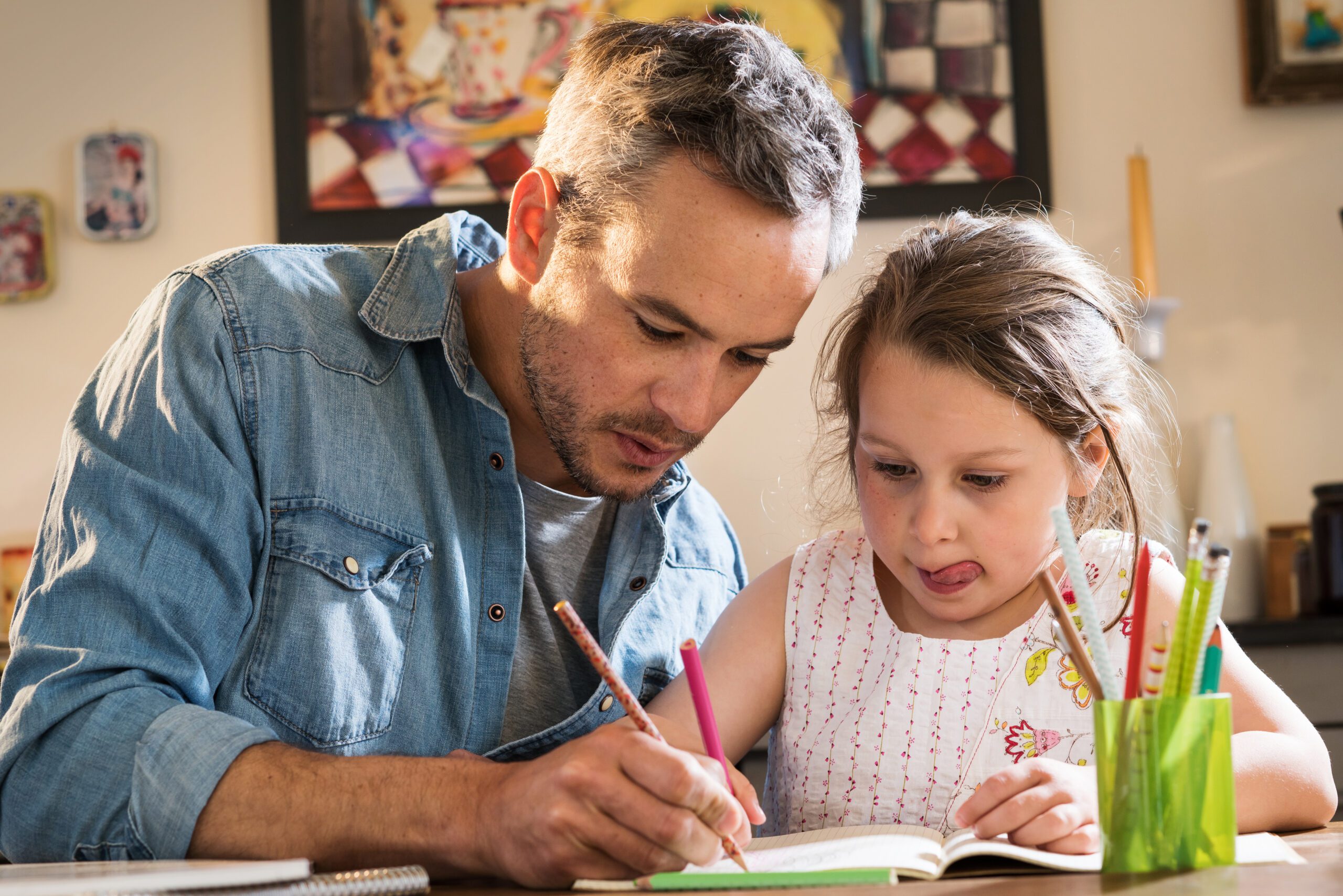 A father helps his daughter with homework.